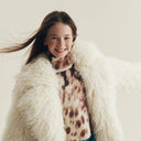 Момиче с пухкаво бяло яке и леопардова блуза от зимната колекция на Gulliver